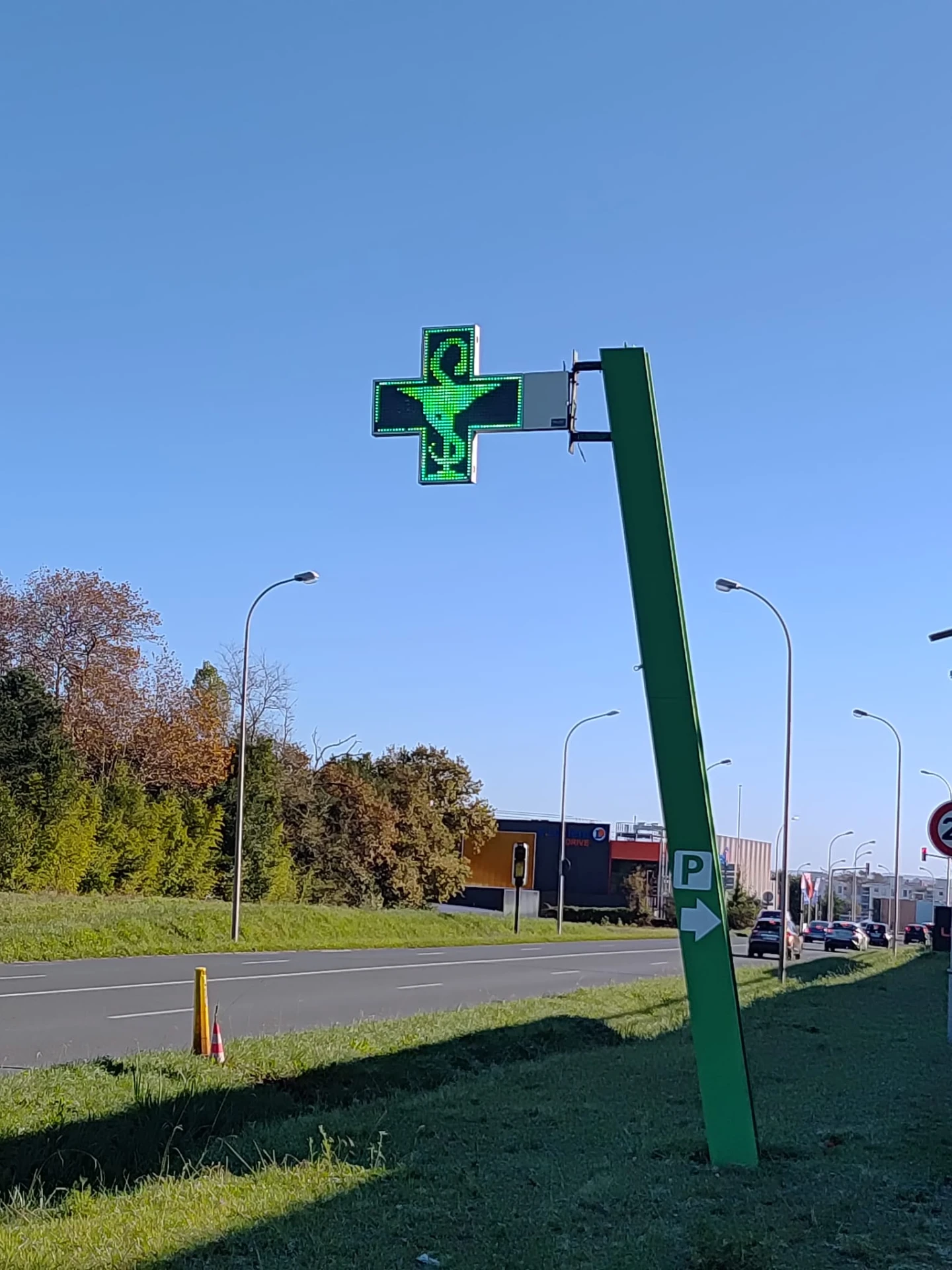 Croix de pharmacie LED sur mât en bord de route
